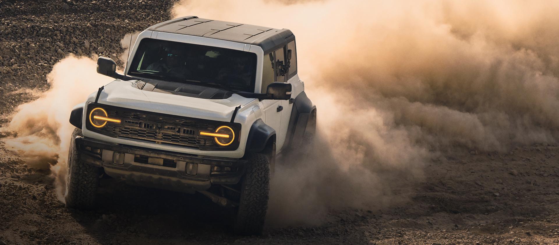 A 2026 Ford Bronco® SUV kicking up dust on a rocky landscape