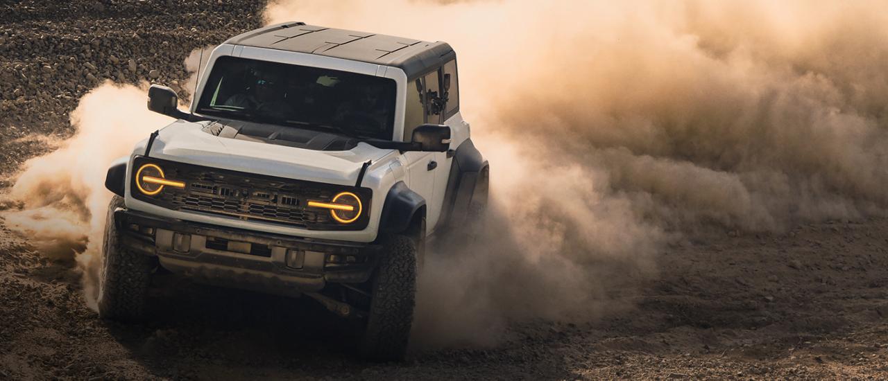 A 2026 Ford Bronco® SUV kicking up dust on a rocky landscape