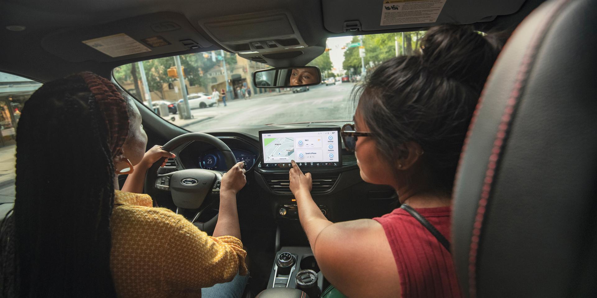 Two women inside a 2026 Ford Escape, while the passenger is looking at the navigation on the center screen