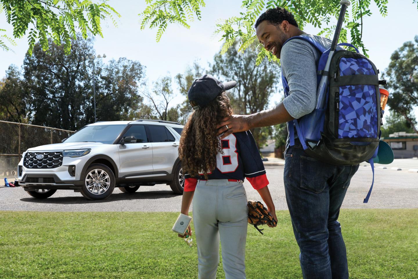 An adult and child walk toward a Ford Explorer.