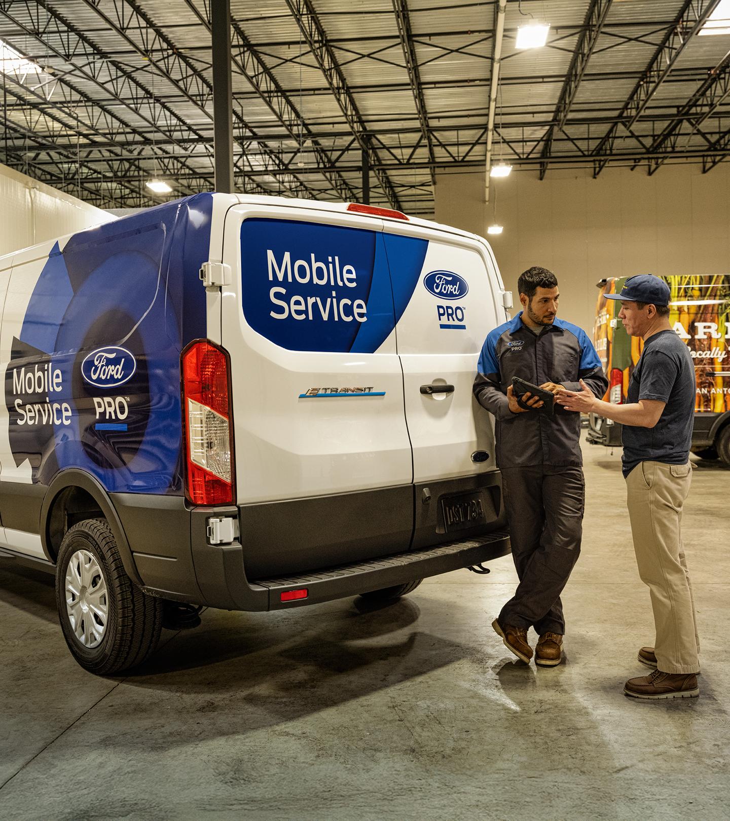 A Ford Mobile Service technician talks to a fleet owner about their vehicle service needs.