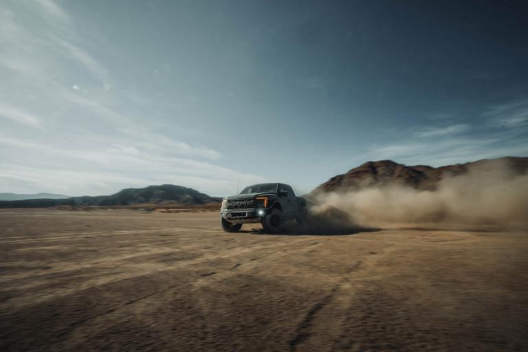 2026 Ford F-150® Raptor® R™ truck being driven in the desert kicking up cloud of sand
