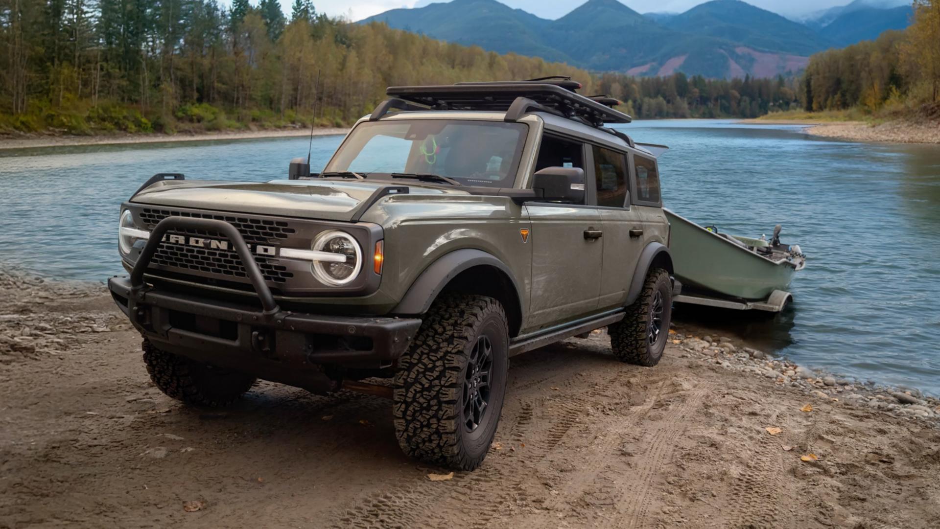 A 2026 Ford Bronco® SUV pulling a boat trailer out of a mountain lake