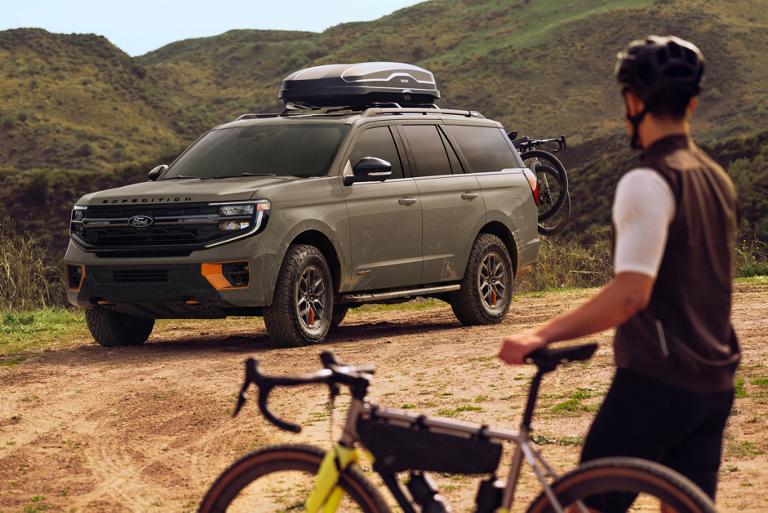 A person on a bicycle near a parked 2026 Ford Expedition® Tremor® model with available Ford accessories