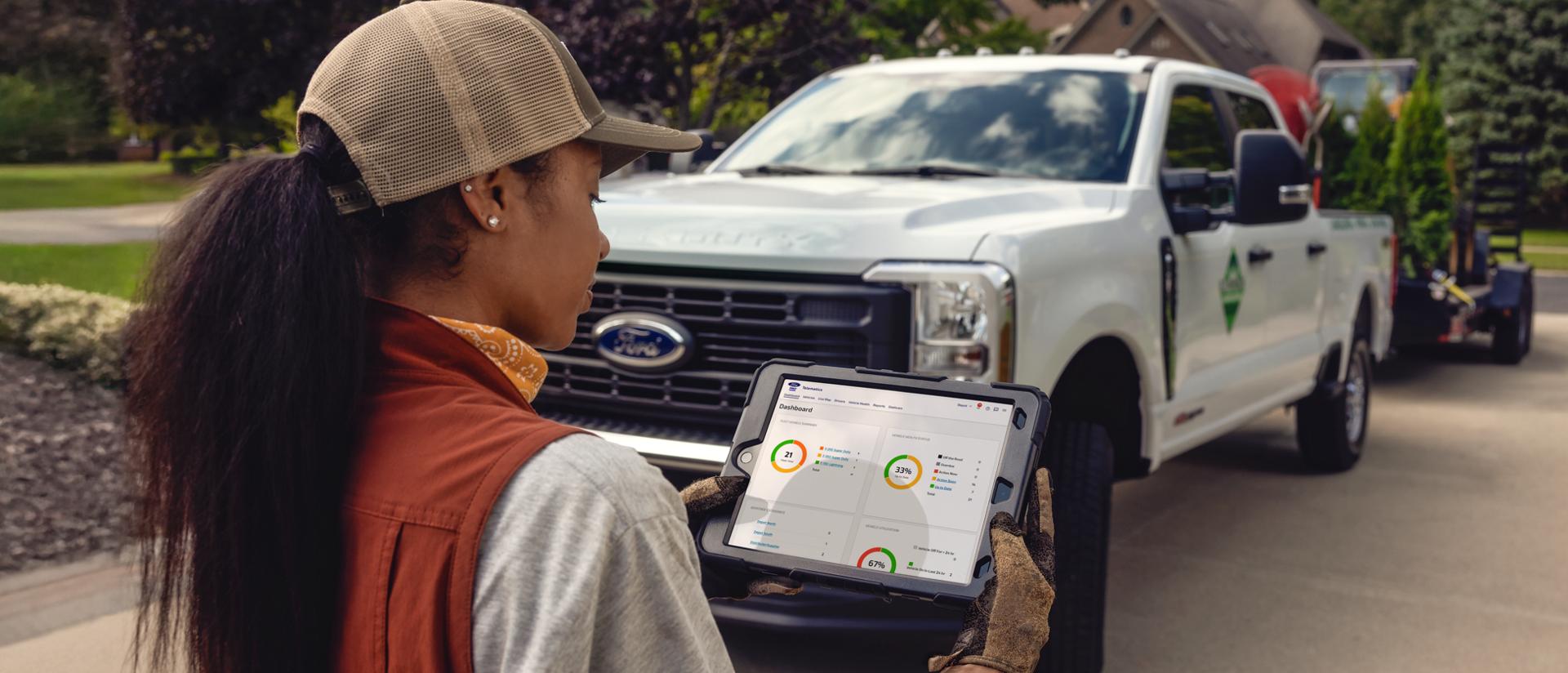 Woman looking at a tablet with a 2026 Ford Super Duty® in the background