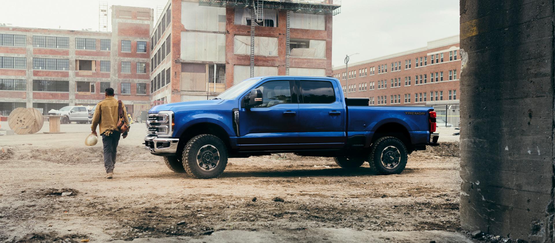 A person walking away from their 2027 Ford Super Duty® F-250® Lariat® pickup in Neptune Blue on a construction site