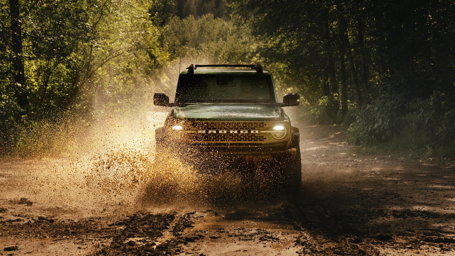 A 2025 Ford Bronco® SUV fording a stream in the forest
