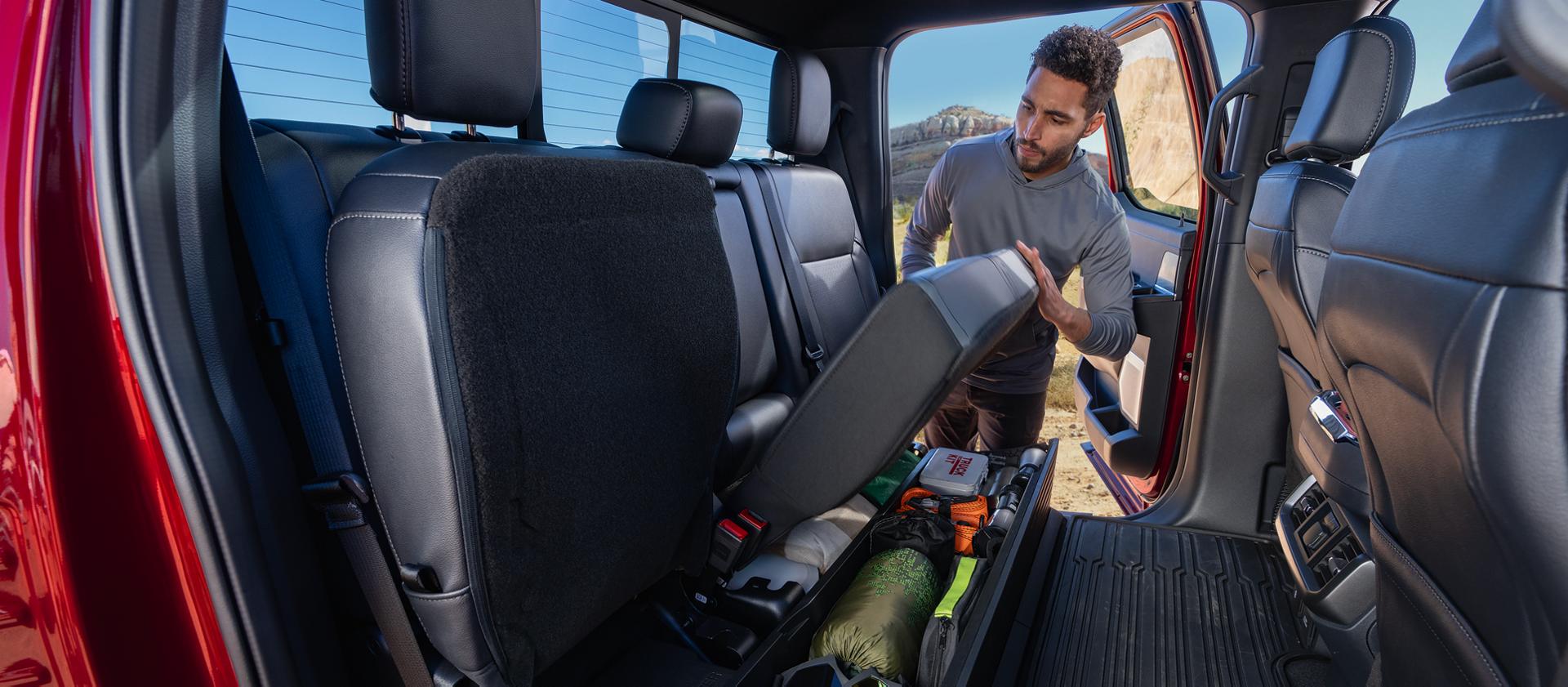 Man lifting the seat of lockable storage feature on a 2026 Ford F-150® pickup