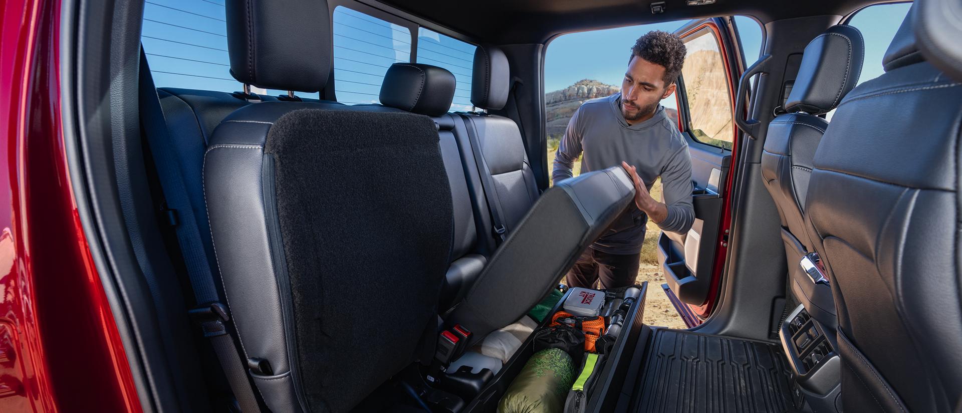 Man lifting the seat of lockable storage feature on a 2026 Ford F-150® pickup
