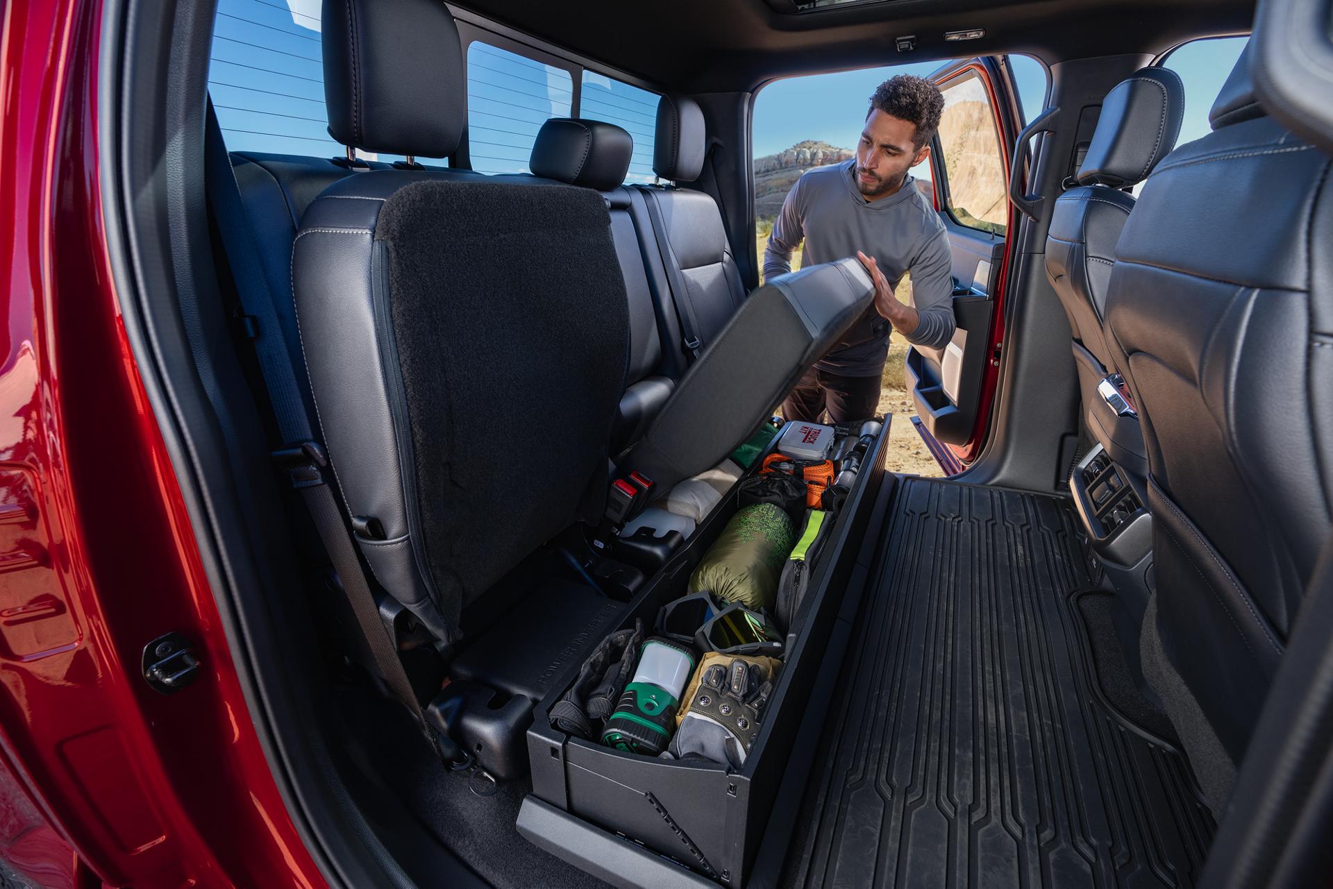 Man lifting the seat of lockable storage feature on a 2026 Ford F-150® pickup