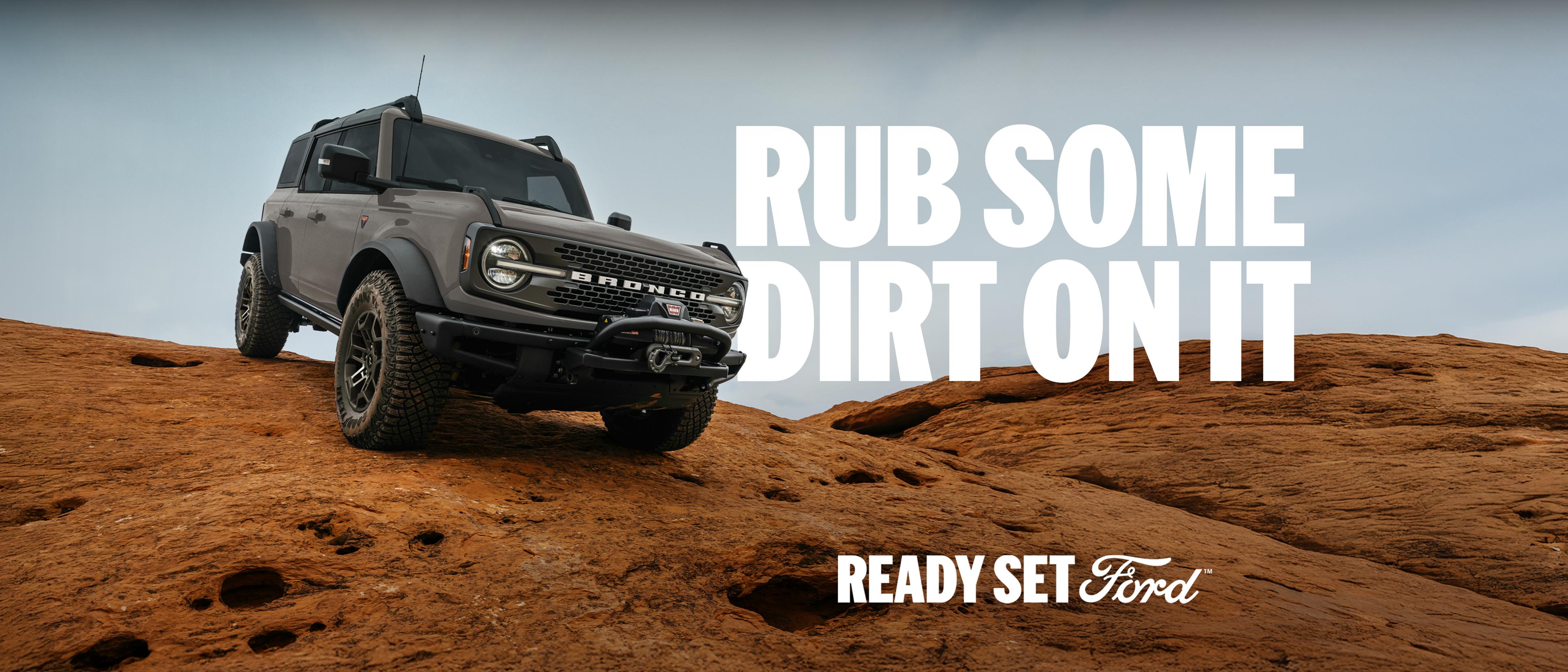 A 2026 Ford Bronco® SUV being driven down a dirt hillside. Caption: “Rub some dirt on it.”
