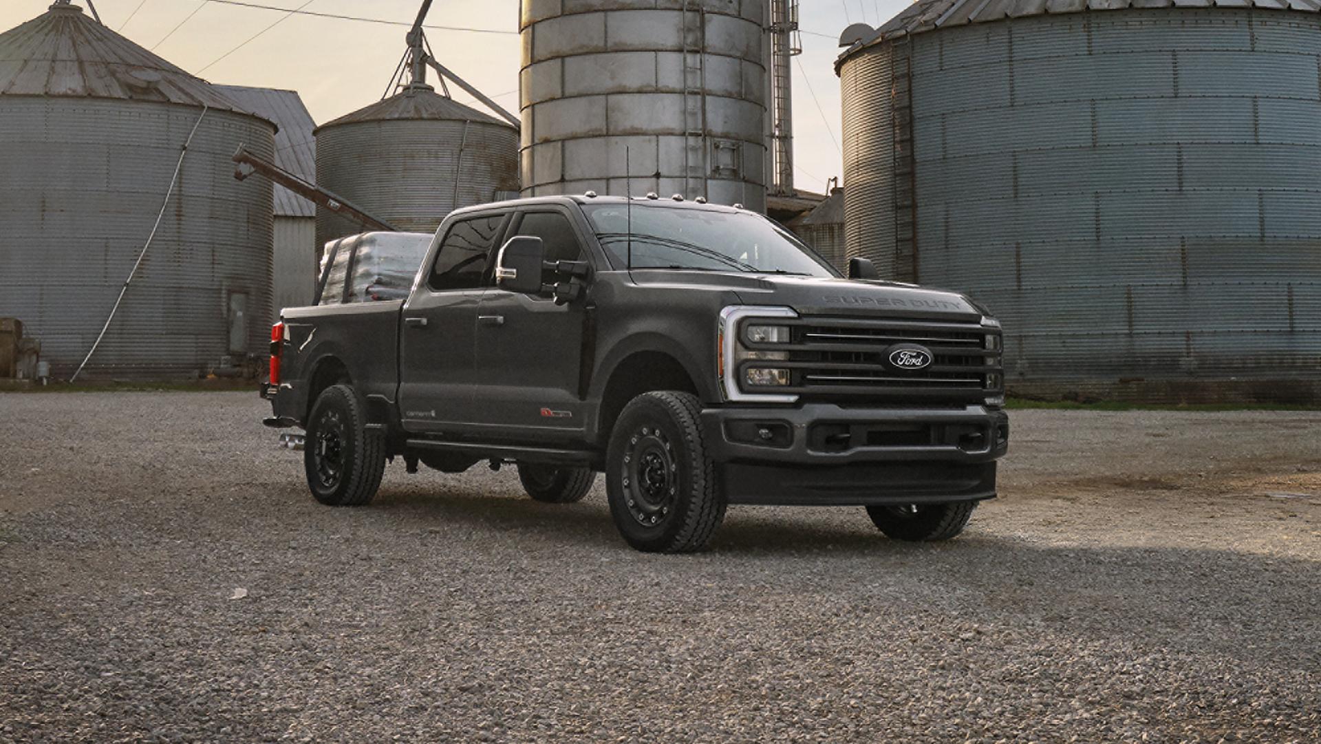 2027 Ford Super Duty® F-350® XLT model with the Super Duty Carhartt® Package parked near large metal silos