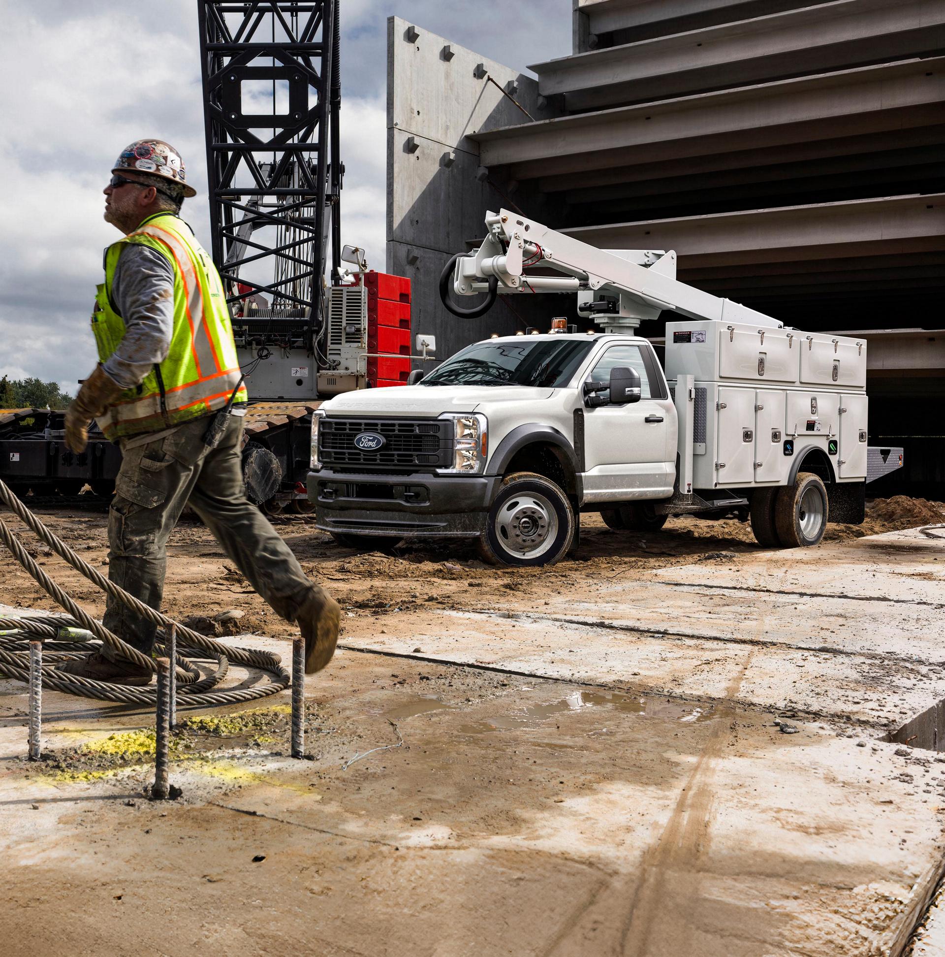 A construction worker walks near a white Ford Super Duty truck parked at a job site.