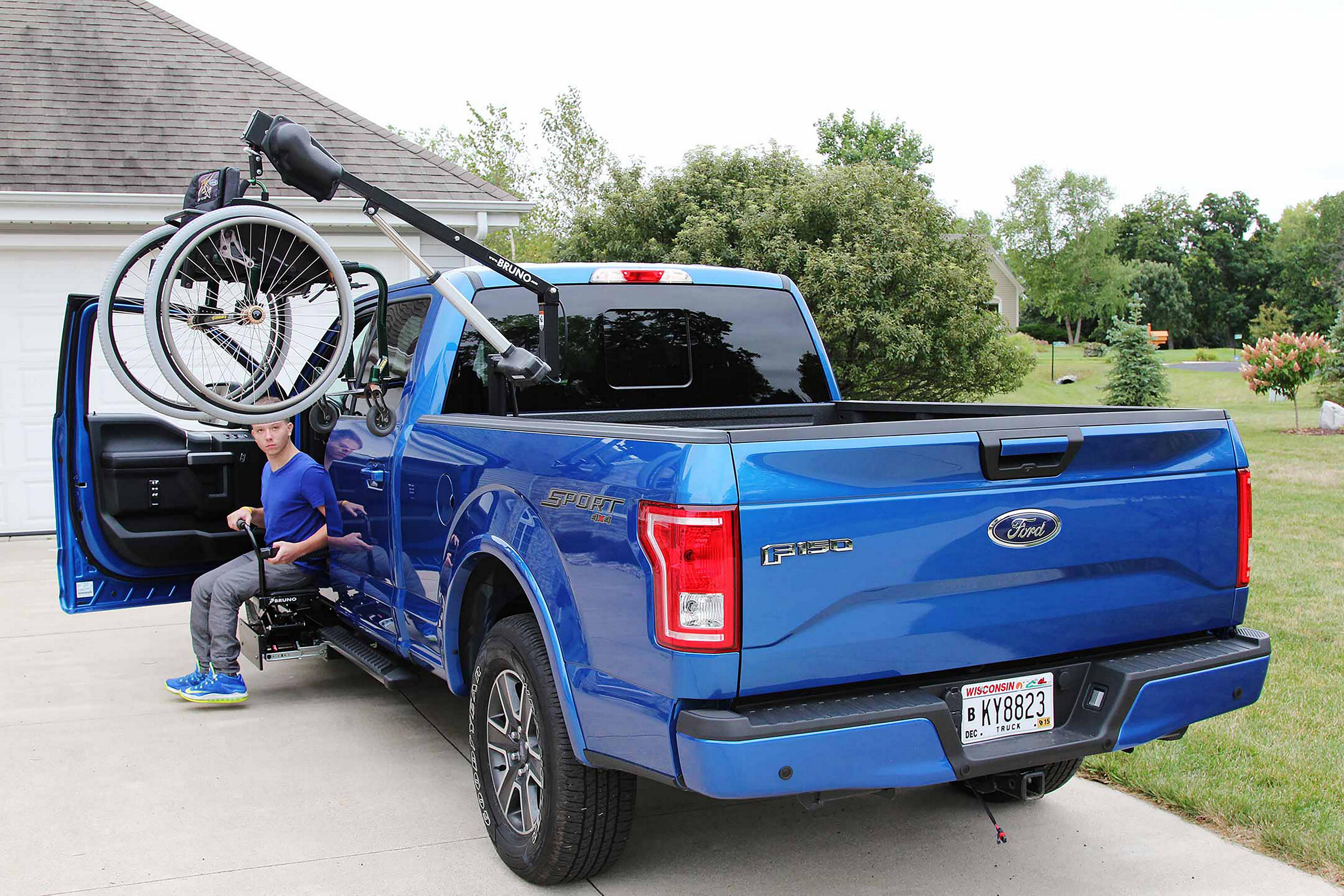 A blue F-150 with a wheelchair hoist in the bed