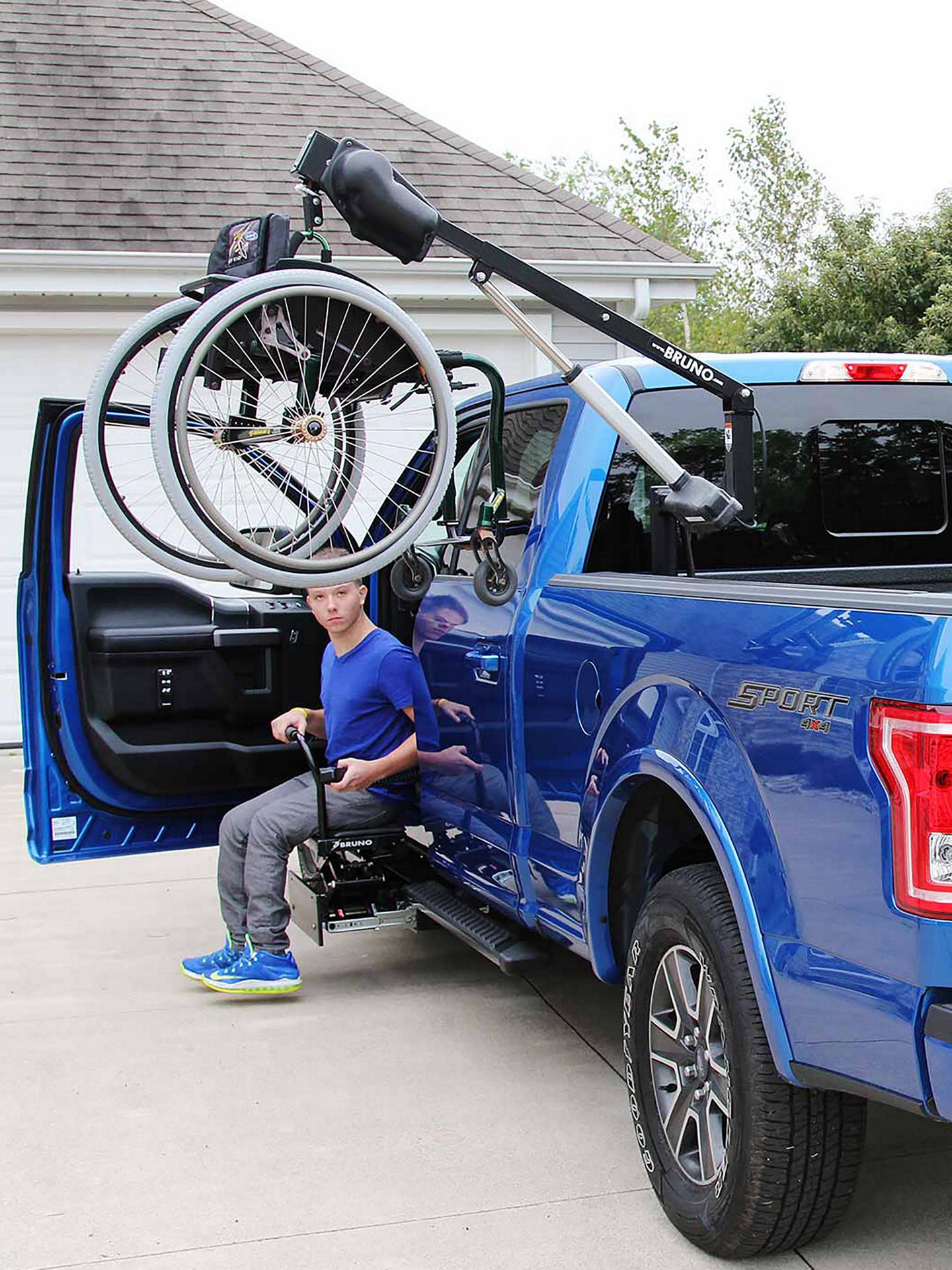 A blue F-150 with a wheelchair hoist in the bed