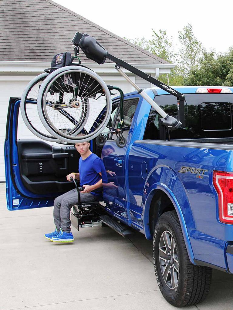 A blue F-150 with a wheelchair hoist in the bed