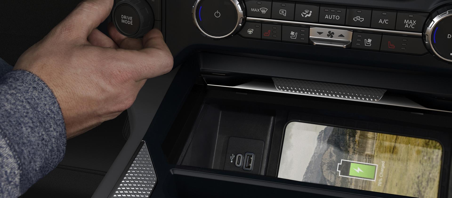 A person's hand adjusting the 2027 Ford Super Duty® pickup Drive Mode knob while a phone charges on the wireless charging pad