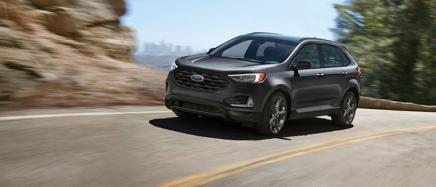 A grey 2024 Ford Edge driving along a highway.
