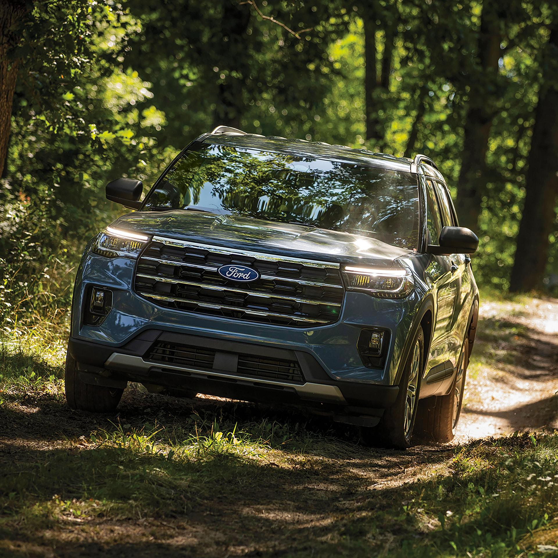A 2027 Ford Explorer® SUV being driven on a dirt trail through the forest