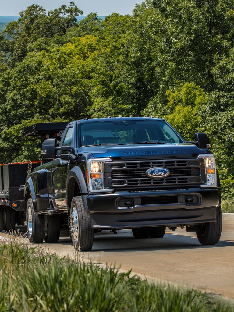 2026 Ford Super Duty® truck towing a large trailer on a paved road