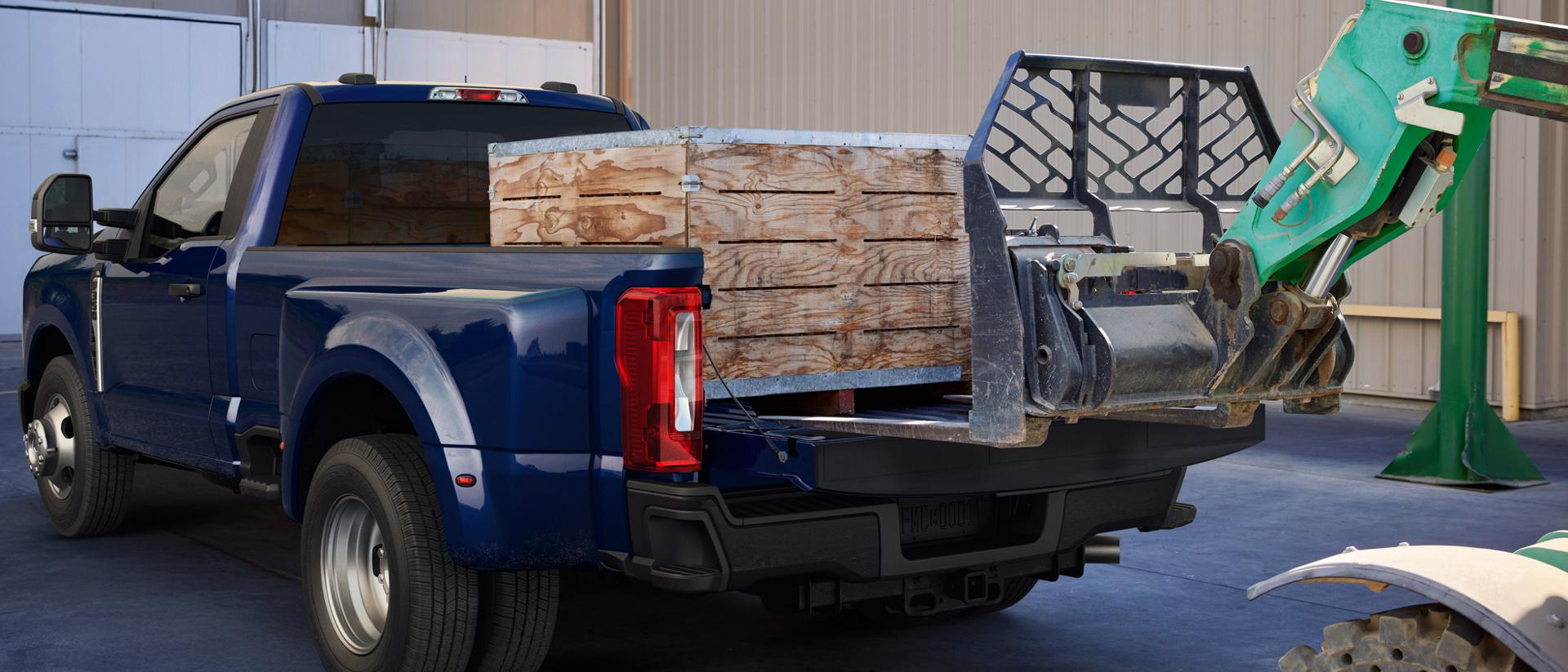 A 2026 Ford Super Duty® F-350® Lariat® model in Argon Blue with heavy crates loaded into the truck bed