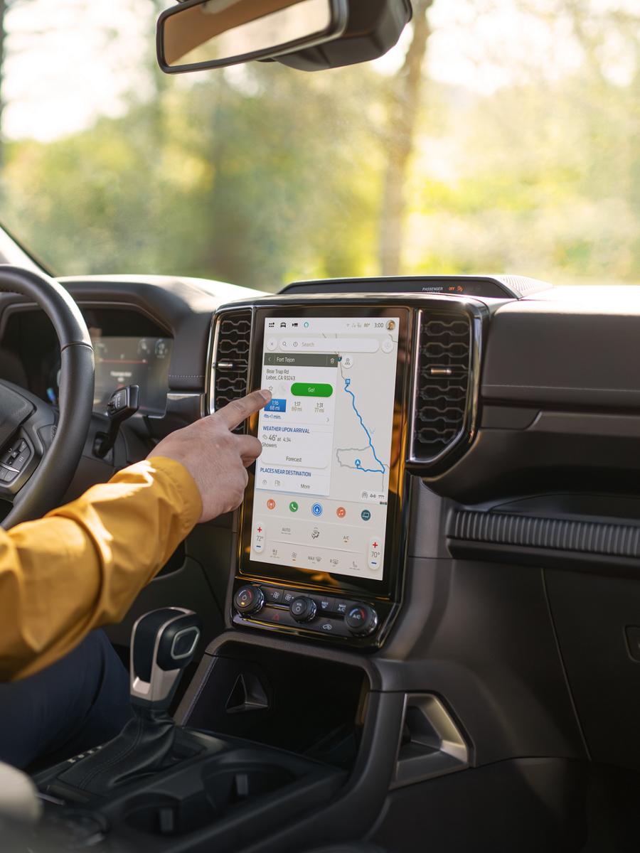 A person's hand using the 12-inch centre display inside their 2026 Ford Ranger® Lariat® truck