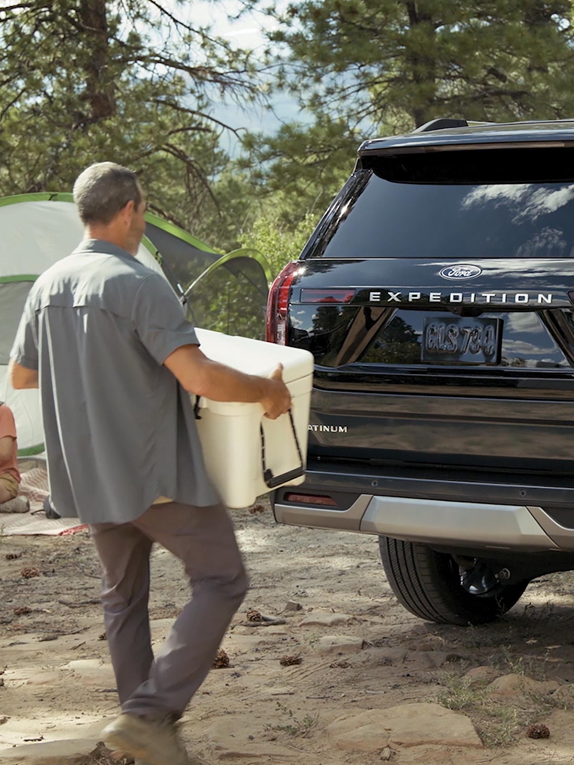 Person using the Ford Split Gate with available Open On Approach to load a cooler in a 2026 Ford Expedition® SUV