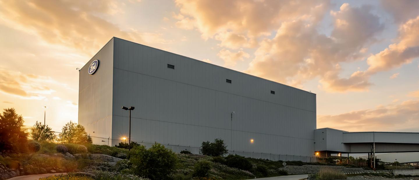 The Ford Oakville Assembly Complex in Oakville, Ontario at sunset, with the Ford logo on the building exterior.