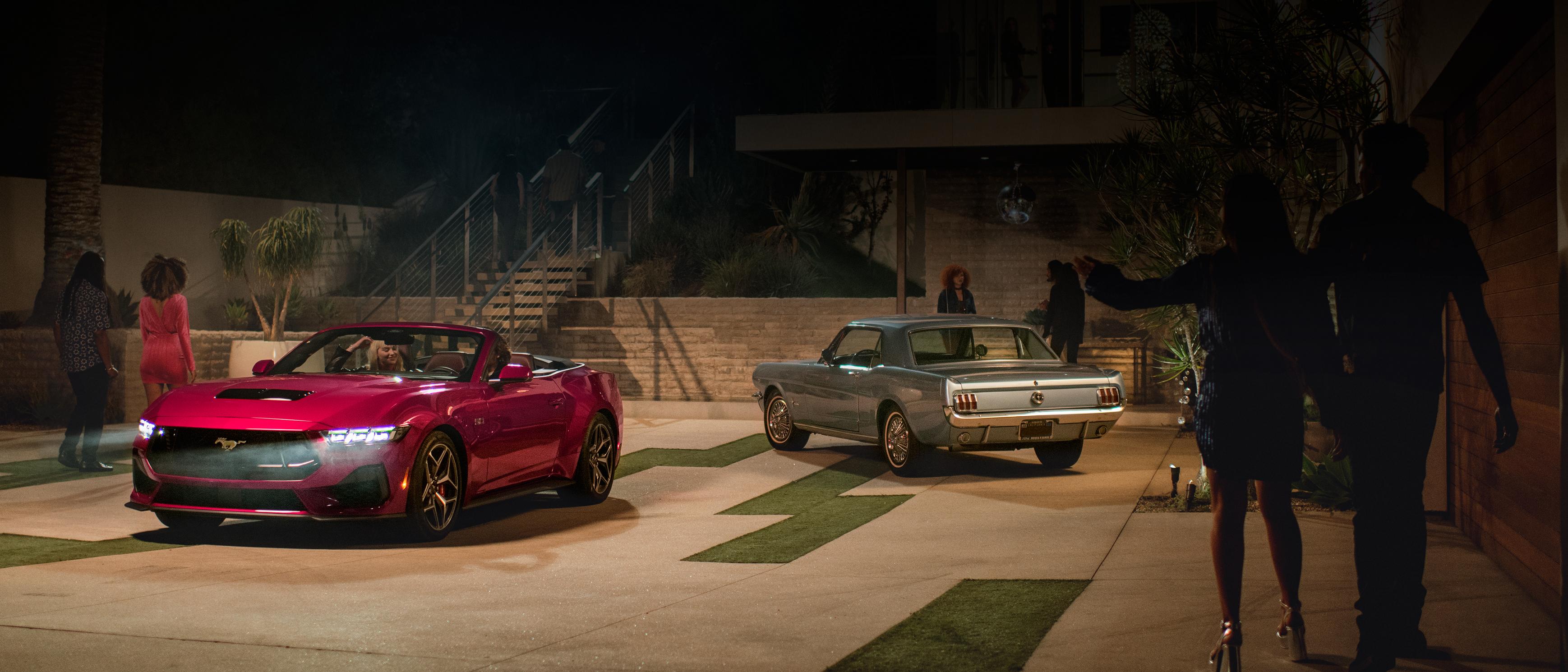 2025 Ford Mustang® GT convertible and a first-gen Mustang coupe parked in a driveway with people nearby