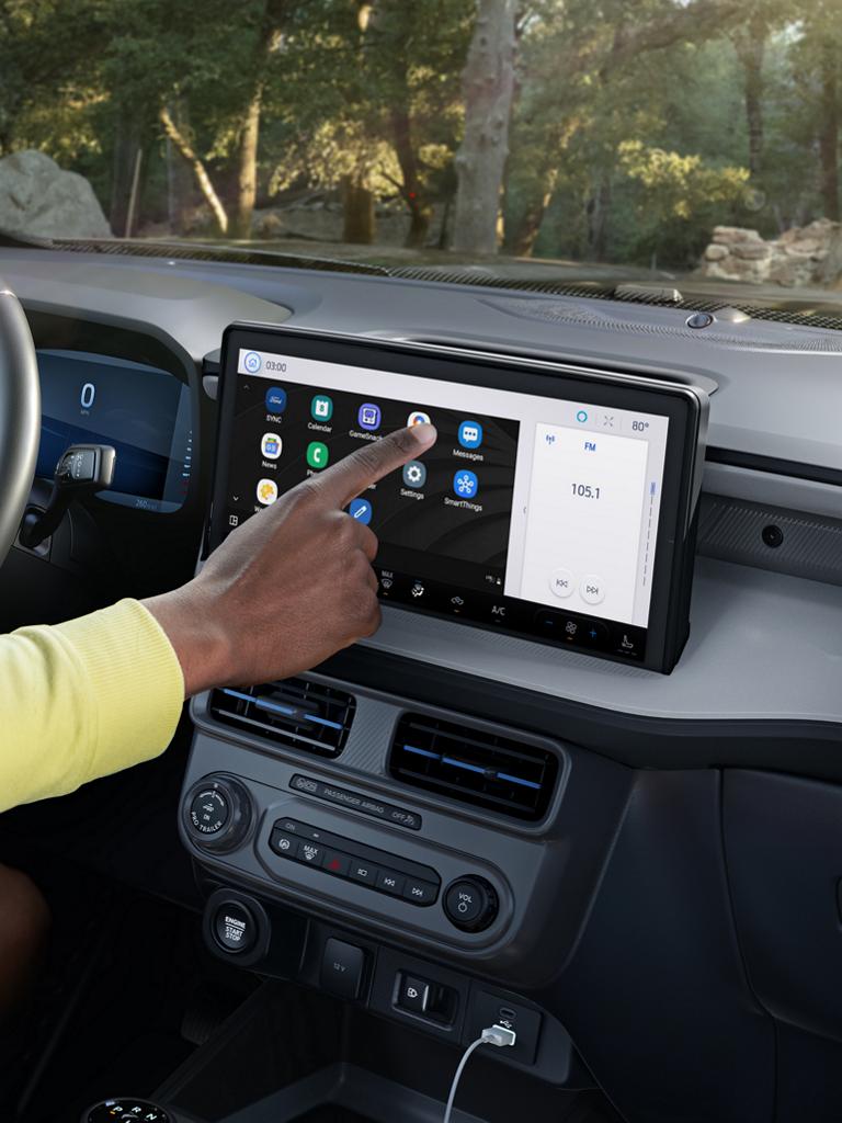A driver using the touchscreen on a parked 2025 Ford Maverick® pickup