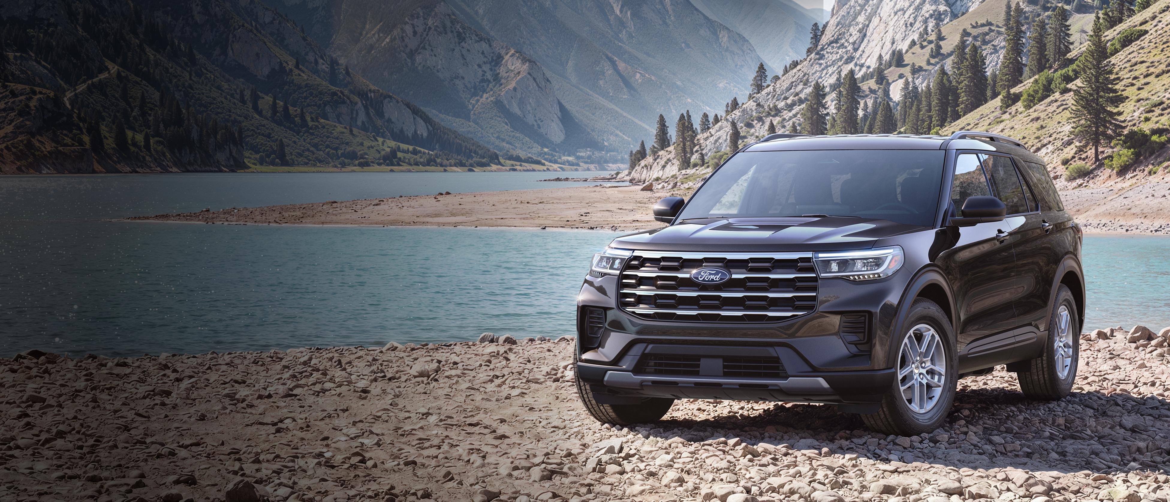 A 2027 Ford Explorer® Active model parked on a rocky expanse near a mountain lake