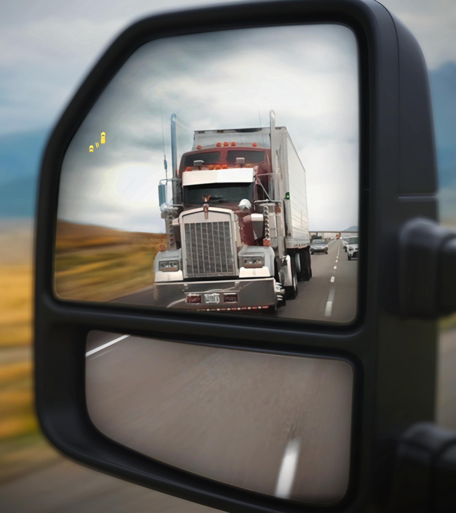 View of the 2026 Ford Super Duty® left side view mirror with a semi truck in the reflection