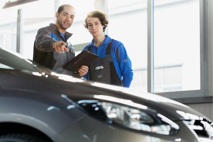 Ford instructor and trainee look at a vehicle.