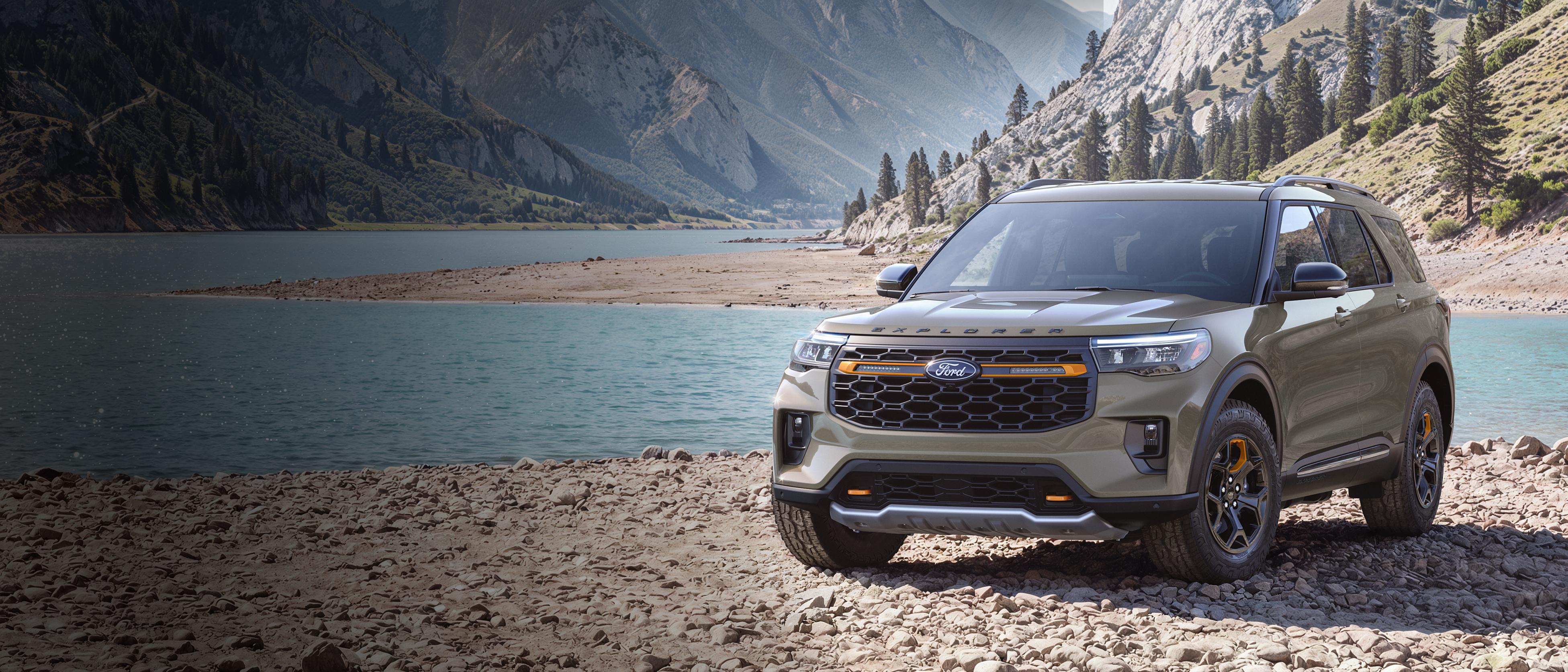 A 2027 Ford Explorer® Tremor® model parked on a rocky expanse near a mountain lake