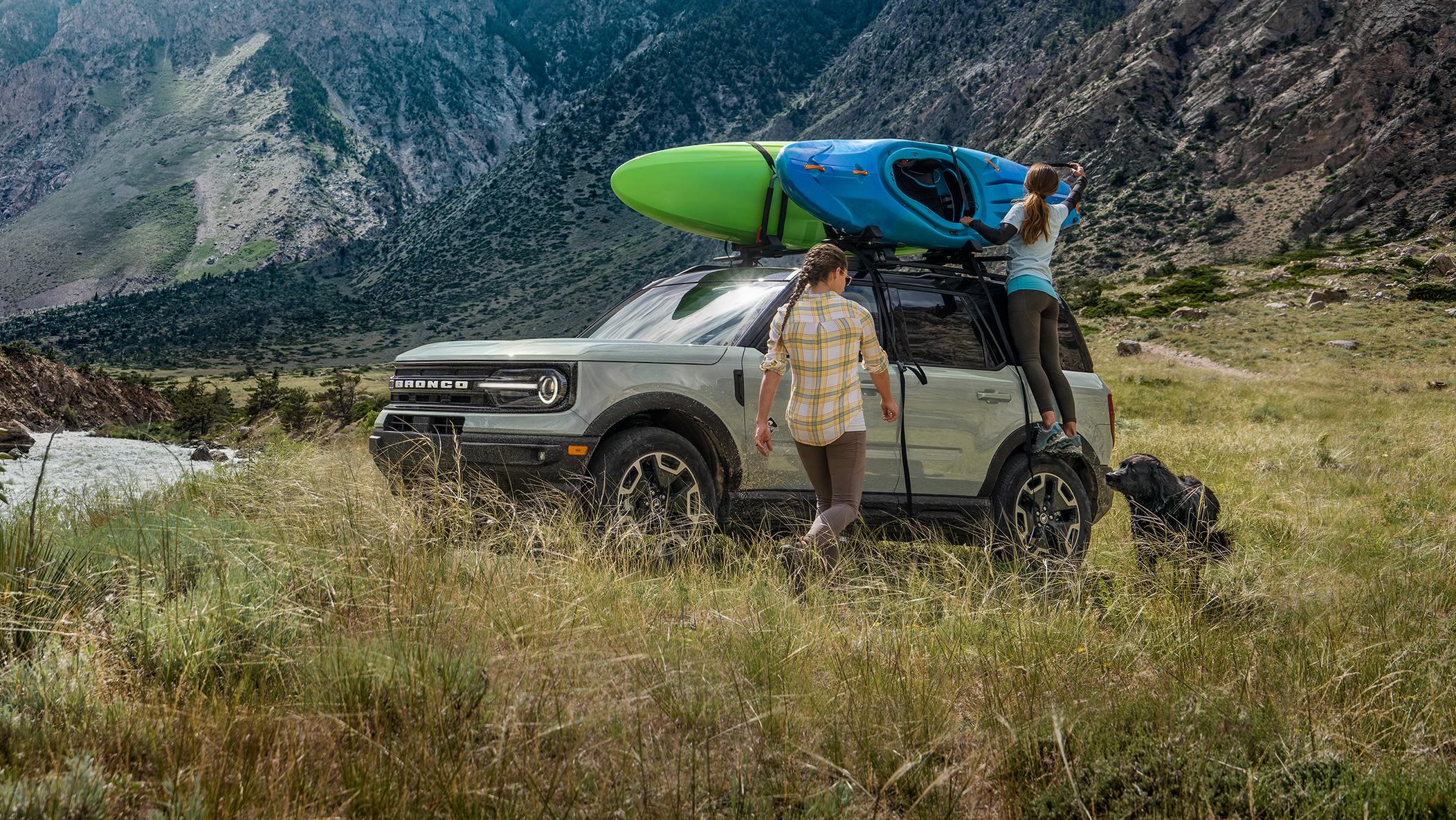 Two people unload a Bronco Sport parked by a lake.