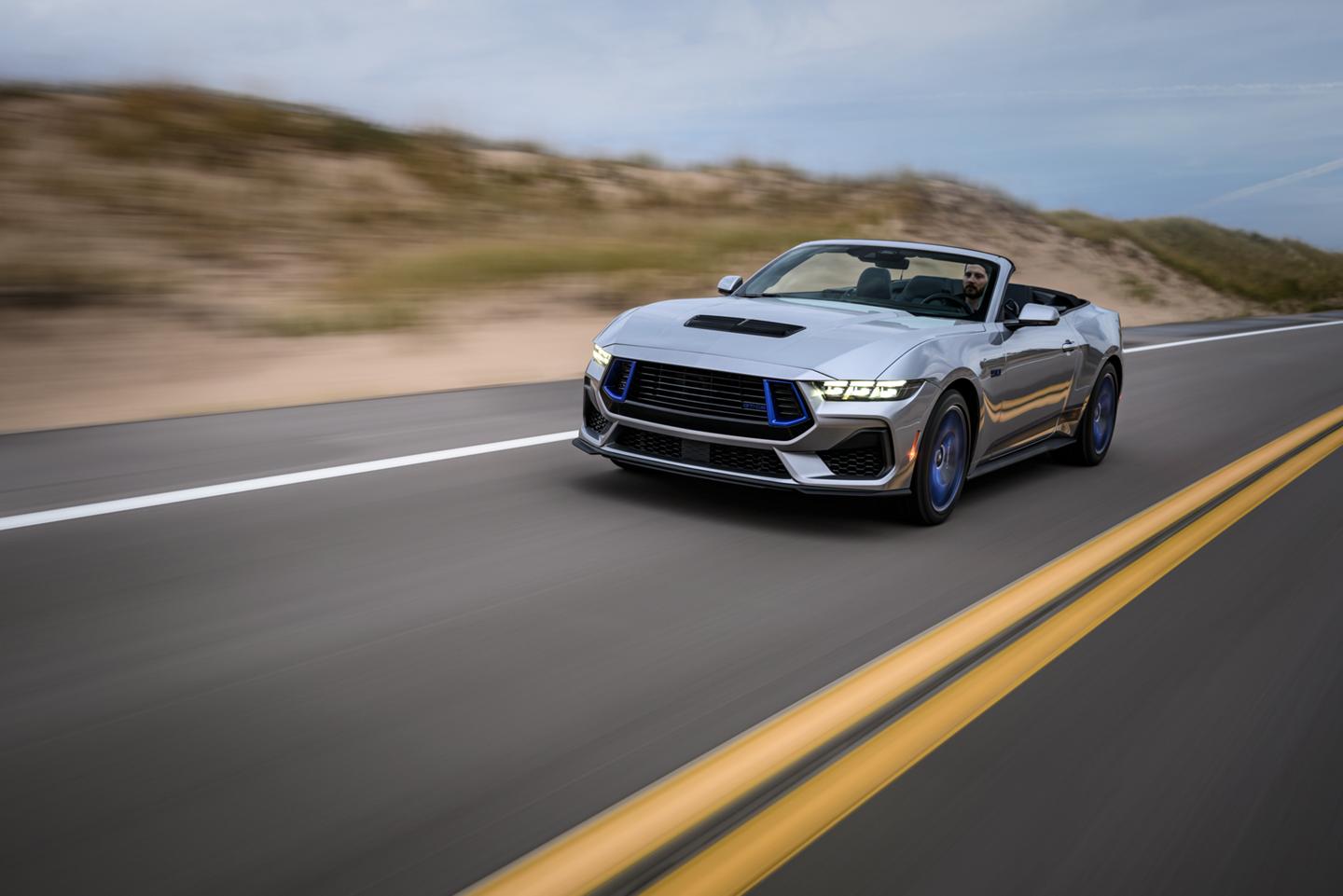 Mustang convertible driving on a two-lane highway.