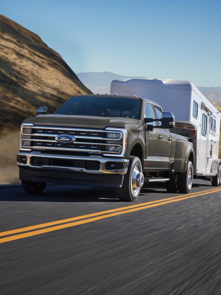 2026 Ford Super Duty® F-350® Lariat® in Marsh grey driving on a paved road with a large trailer