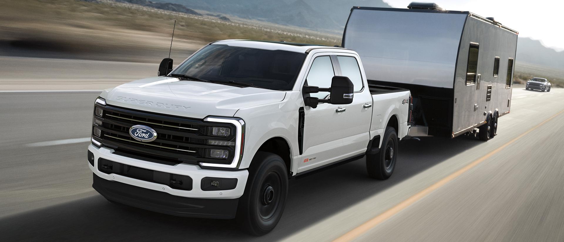 A 2027 Ford Super Duty® F-350® Platinum® model pulling a large camper on a paved road