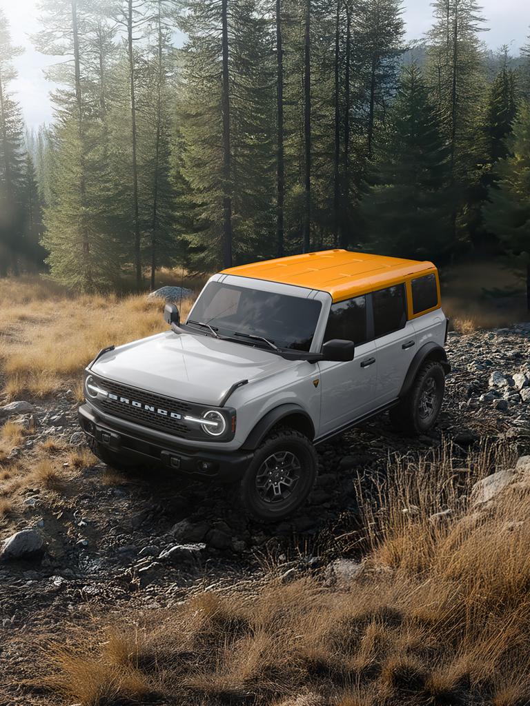 A 2026 Ford Bronco® SUV on a muddy path, with a light-coloured body and a orange roof