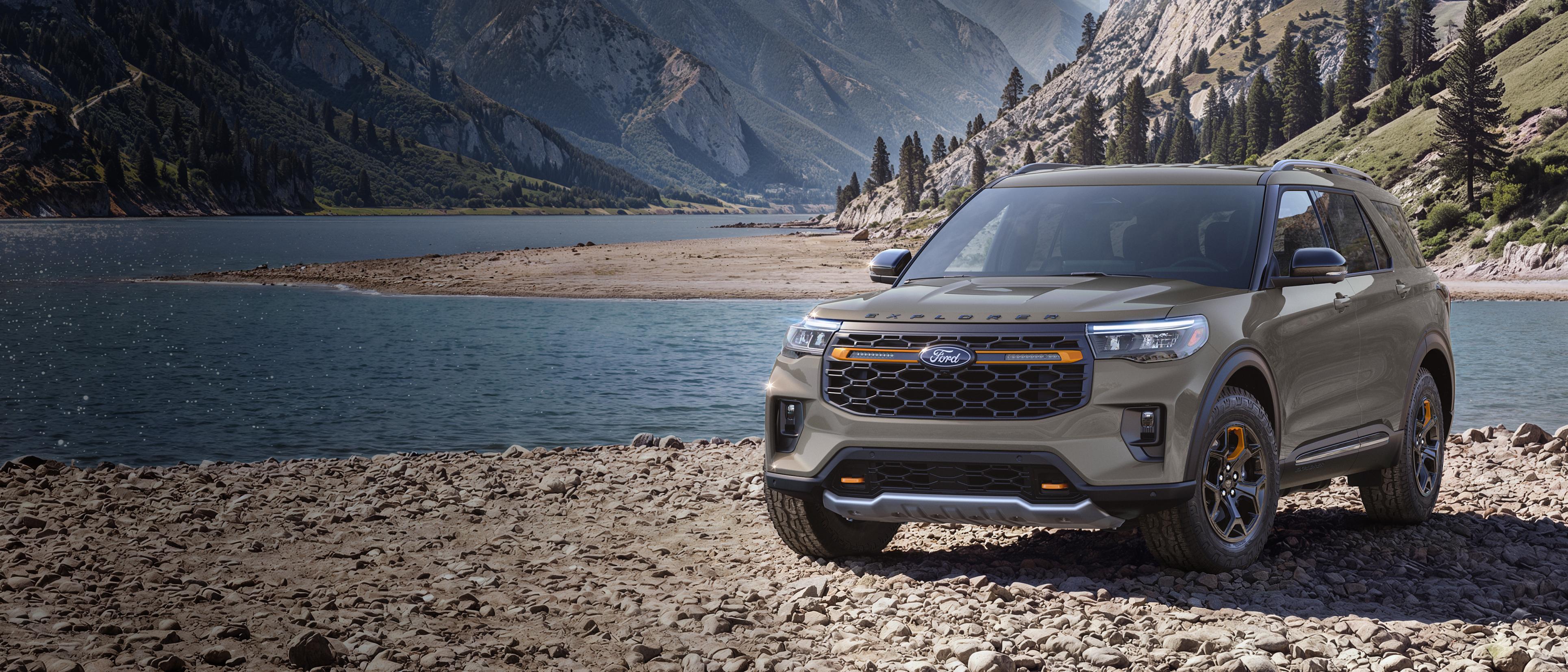 A 2027 Ford Explorer® Tremor® model parked on a rocky expanse near a mountain lake