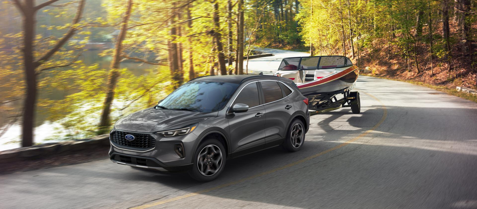 2026 Ford Escape® with 2.0L EcoBoost® engine towing a boat on a tree-lined road