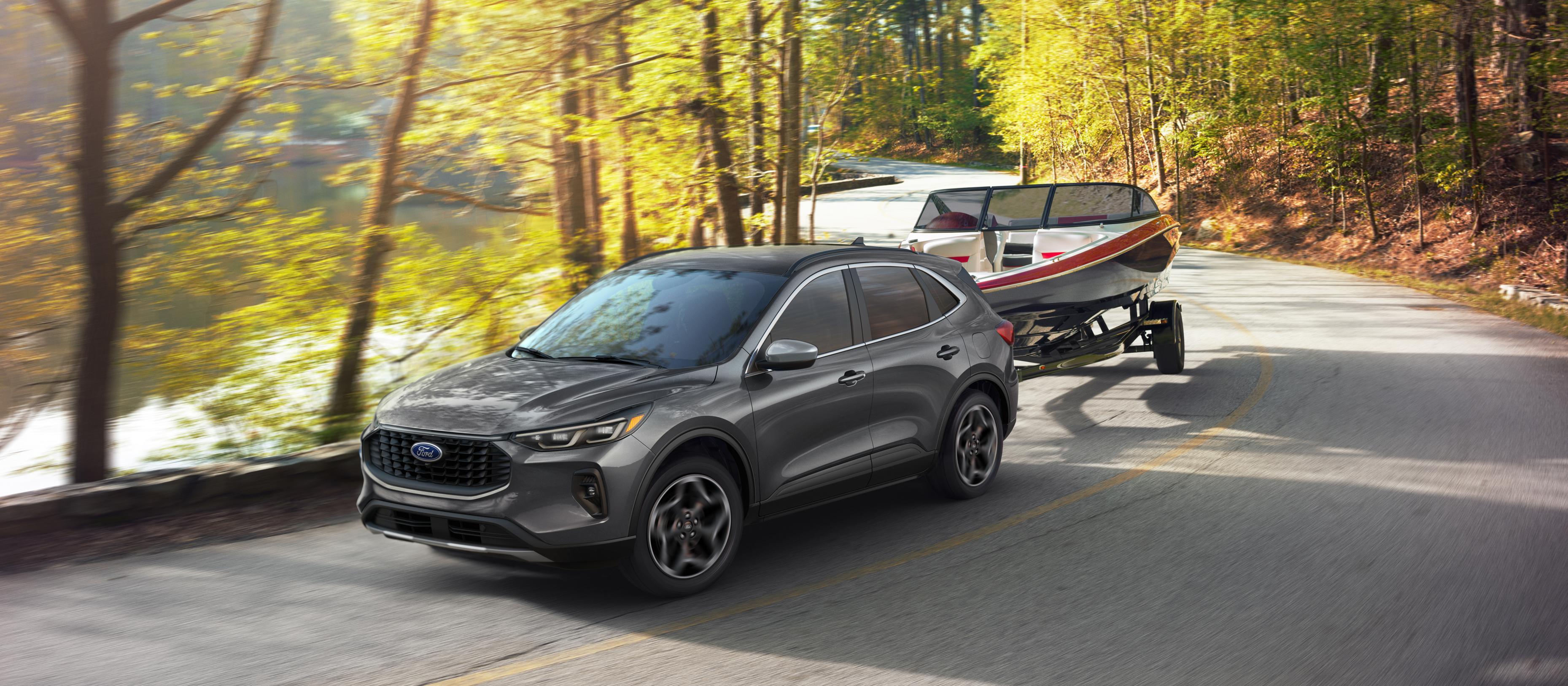 2026 Ford Escape® SUV towing a small boat on a lake road