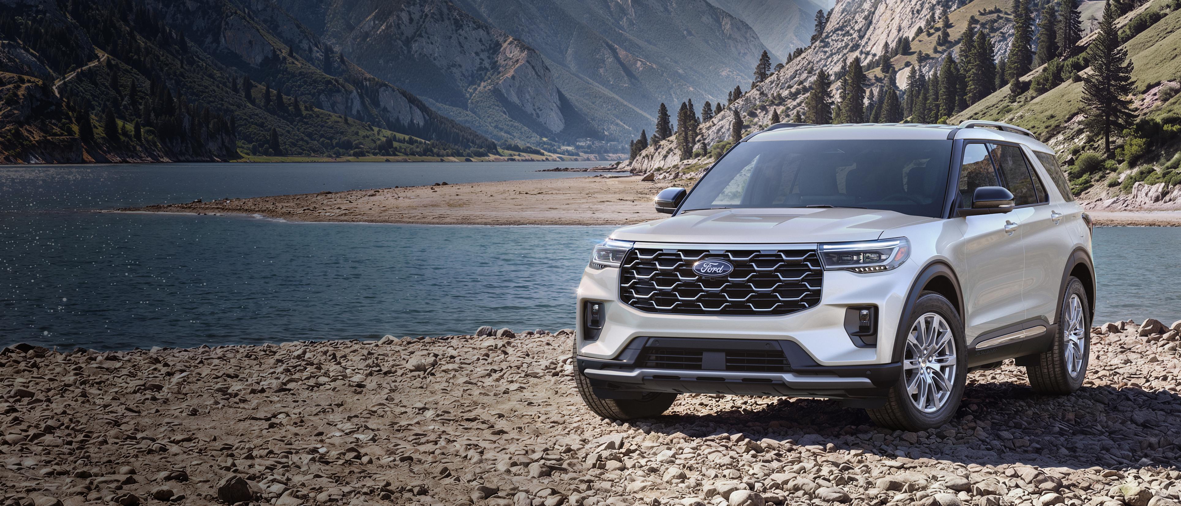 A 2027 Ford Explorer® Platinum™ model parked on a rocky expanse near a mountain lake