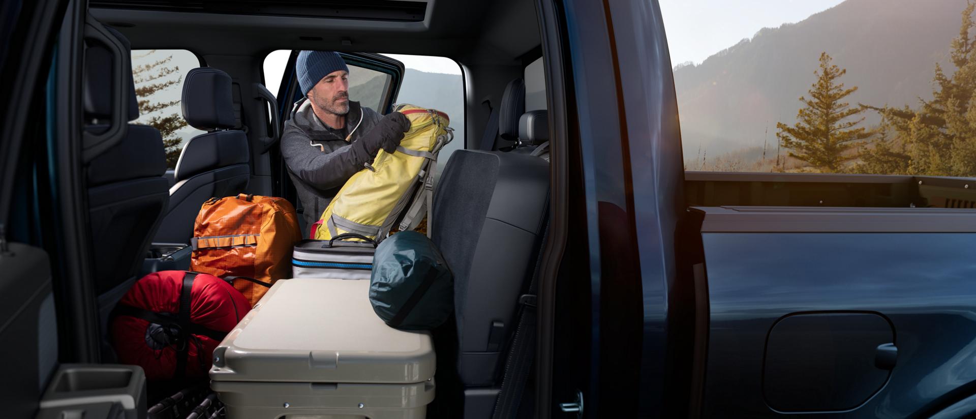 Man loading gear inside a 2026 Ford F-150® pickup highlighting flip and fold seats