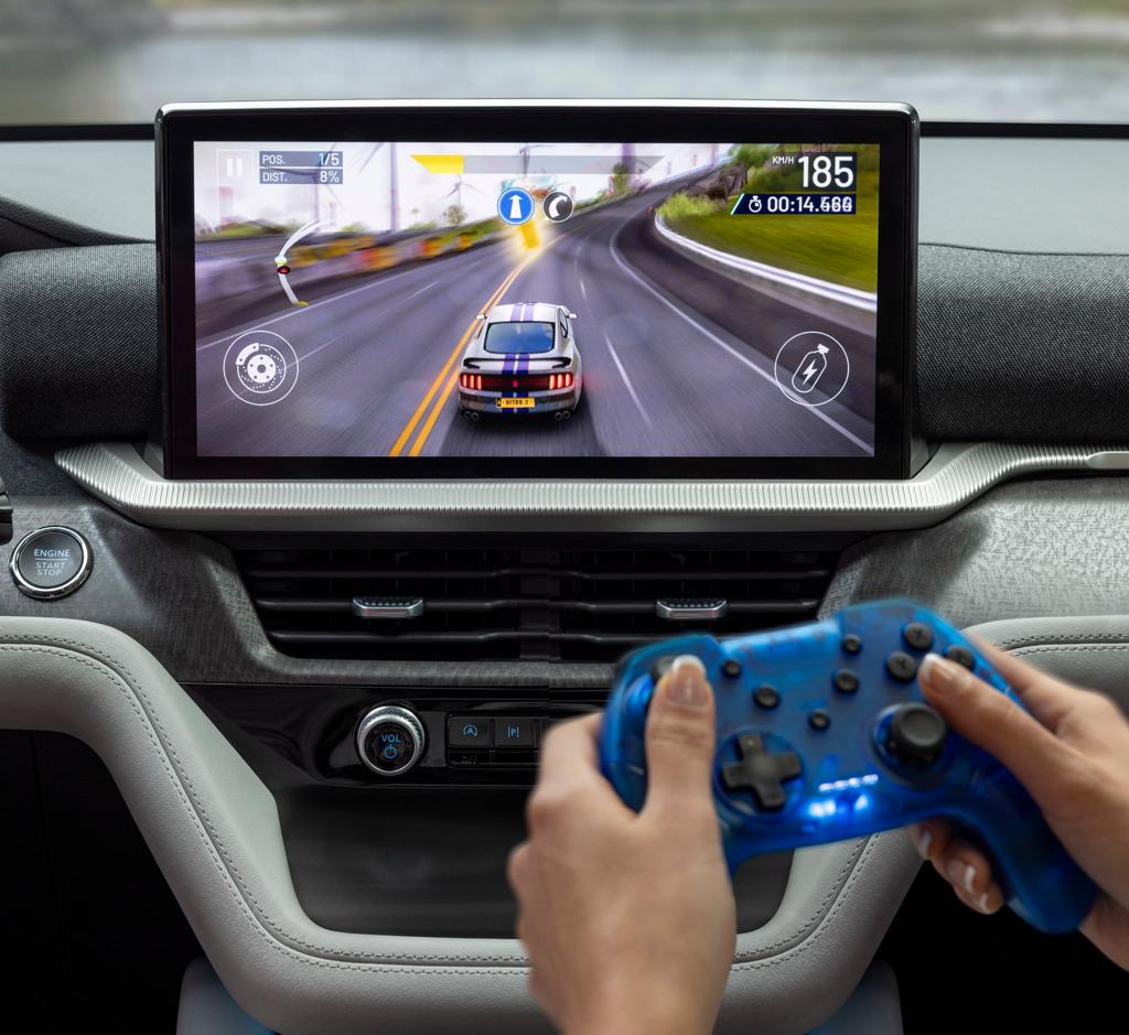 A passenger playing a racing game on the centre display of a parked 2026 Ford Explorer® SUV
