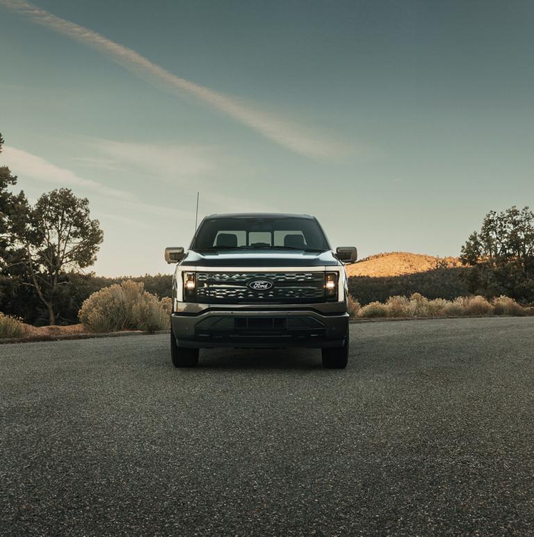 A 2025 Ford F-150® Lightning® is head on parked at sunset in a scenic location