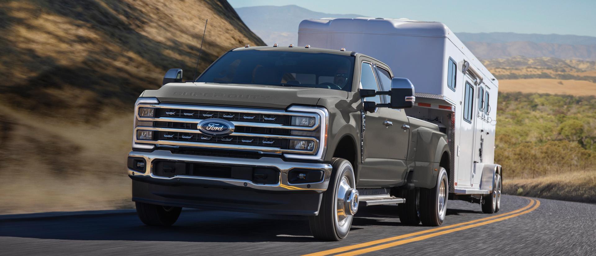 2026 Ford Super Duty® F-350® Lariat® in Marsh grey driving on a paved road with a large trailer
