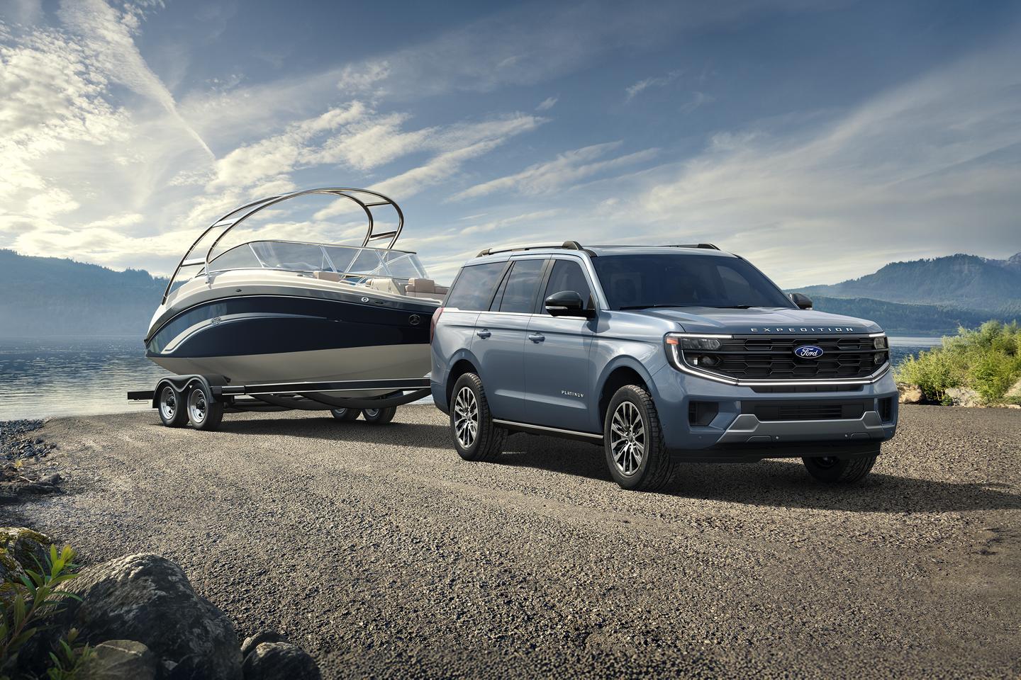 A Ford Expedition with a hitched boat parked on a gravel path by a lake.