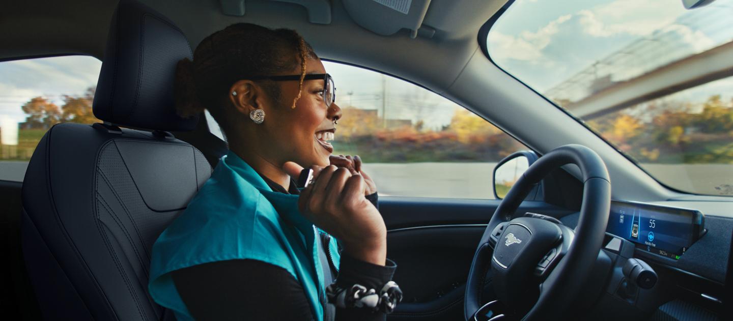 A woman behind the wheel of a 2025 Ford Mustang Mach-E® with her hands off the wheel
