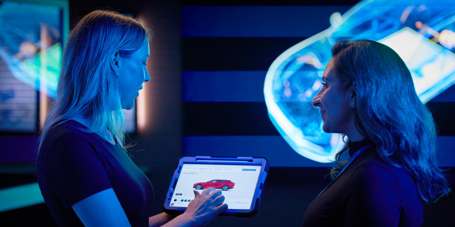 Two Ford employees review an image on a tablet.
